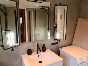 a bathroom with a white sink and two mirrors at Lillesjö stuguthyrning in Bäckefors +218 photos