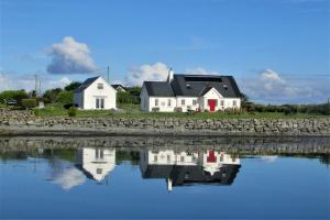 a house sitting next to a stone wall and water at Breacan Cottage B&B in Kinvara