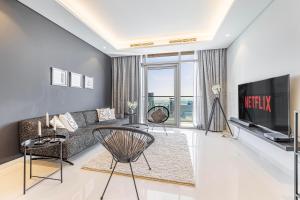 uma sala de estar com um sofá e uma televisão em 2 BR Superior High Floor Apartment in Paramount Midtown, Burj Khalifa View em Dubai