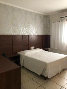 - une chambre avec un grand lit blanc et une fenêtre dans l'établissement Hotel Residence, à Dourados