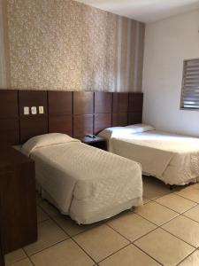 Dos camas en una habitación de hotel con ermott en Hotel Residence, en Dourados