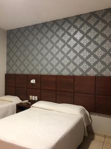 1 dormitorio con 2 camas y pared con papel pintado en Hotel Residence, en Dourados