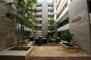 a lobby of a building with palm trees and chairs at Apartamento Flat Ecosummer Tambaú in João Pessoa