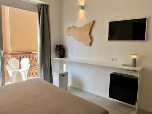 タオルミーナにあるDon Diego Luxury Roomsのベッドと壁掛けテレビのある寝室