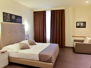 ein Hotelzimmer mit einem großen Bett und einem Stuhl in der Unterkunft Duomo Hotel & Apartments in Mailand