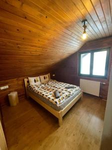 Cama en habitación con techo de madera en Madarasi Sportbázis en Căpîlniţa