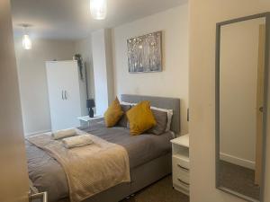 um quarto com uma cama com almofadas amarelas e um espelho em stylish two bed in the heart of the city em Birmingham