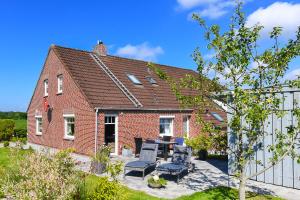 une maison en briques avec une table et des chaises dans une cour dans l'établissement Nordsee Landhuus Heinken, à Stedesdorf