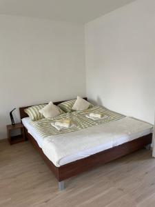 a bed in a bedroom with a white wall at AA Apartman in Kaposvár