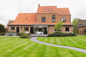 a large brick house with a grass yard at Vakantievilla Leonie in Lo-Reninge