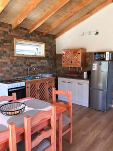 cocina con mesa y nevera de acero inoxidable en Cabañas Los Zorzales, en Puerto Montt