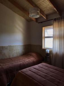 1 dormitorio con 2 camas y ventana en Cabañas Los Zorzales, en Puerto Montt