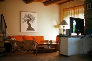 a living room with an orange couch and a table at Villa I Camini - Outbuilding, dependance - Swimming pool - Garden - BBQ and fireplaces - Soccer field in Monte Castello di Vibio