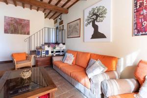 a living room with an orange couch and a table at Villa I Camini - Outbuilding, dependance - Swimming pool - Garden - BBQ and fireplaces - Soccer field in Monte Castello di Vibio