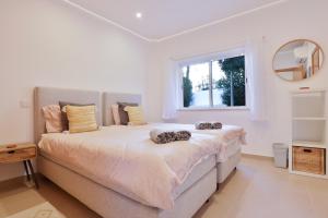 a white bedroom with a large bed with a window at Casa Rujo - Waterside Village House in Luz