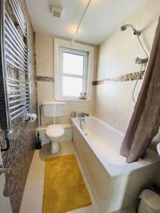 uma casa de banho com uma banheira, um WC e uma janela. em Castle View 2 Bedroom Apartment in Town Centre em Hastings