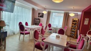 a dining room with pink chairs and tables at Pensiunea Sofia in Pecica Veche