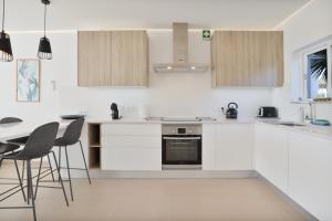 a kitchen with white cabinets and a table and chairs at Casa Rujo - Waterside Village House in Luz