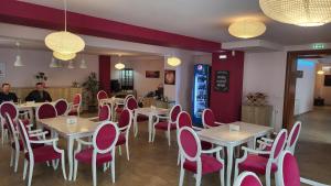 a restaurant with white tables and pink chairs at Pensiunea Sofia in Pecica Veche