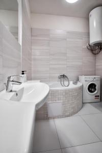 a white bathroom with a sink and a washing machine at Archibald Flats Prague in Prague