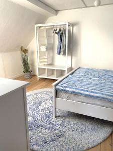 ein weißes Schlafzimmer mit einem Bett und einem Teppich in der Unterkunft Insel Hus in Fehmarn