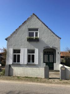 una casa gris con una puerta verde y una ventana en Insel Hus, en Fehmarn