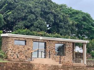 a stone house with a tree in the background at Hazyview Accommodation, Bon Repose Cottage 1 in Hazyview