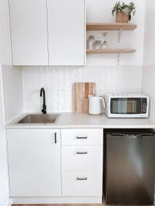 a white kitchen with a sink and a microwave at The Hideaway - Guest House in Warrnambool