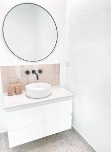 Baño blanco con lavabo y espejo en The Hideaway - Guest House en Warrnambool