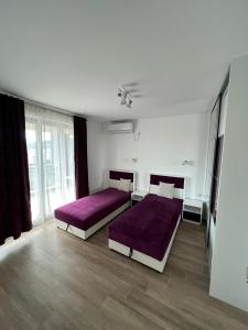 sypialnia z 2 łóżkami i fioletową pościelą w obiekcie Apartments Meri w Dobrej Vodzie