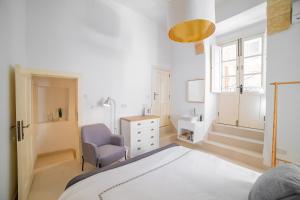 ein Schlafzimmer mit einem Bett, einem Stuhl und einem Waschbecken in der Unterkunft Carmelita Maisonette Valletta in Valletta