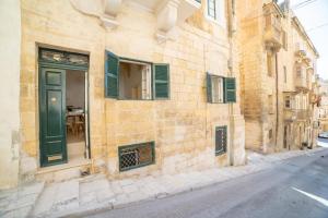 ein Gebäude mit grüner Tür auf einer Straße in der Unterkunft Carmelita Maisonette Valletta in Valletta