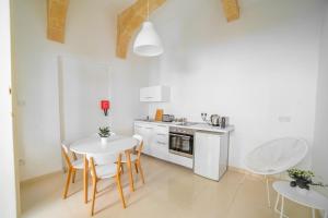 a white kitchen with a table and chairs and a sink at Carmelita Maisonette Valletta in Valletta