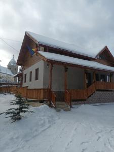 a house with snow on the roof of it at Pensiunea Floare de Colt in Beliş
