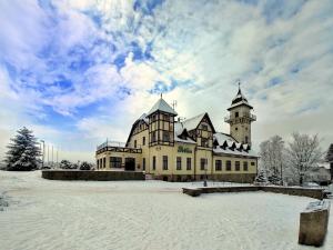 a large building with two towers in the snow at hotel Petřín in Jablonec nad Nisou