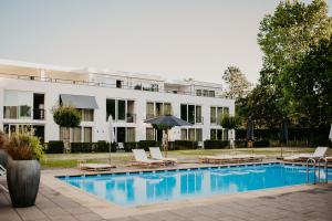 a hotel with a swimming pool in front of a building at Hotel de Zeeuwse Stromen - Duinpark in Renesse