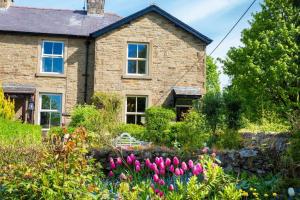 a stone house with a garden in front of it at SUNNYBECK COTTAGE Award winning DOG friendly in Settle