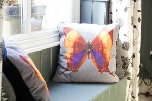 a butterfly pillow sitting on a window sill at SUNNYBECK COTTAGE Award winning DOG friendly in Settle