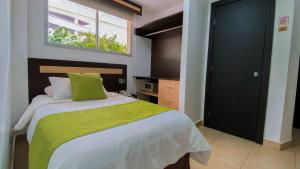 a bedroom with a bed with a green blanket and a window at MC Suites Boutique in Guayaquil