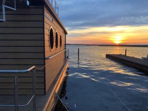 温德托尔夫Hausboot Fjord Luna mit Biosauna in Wendtorf的水面上的建筑,背景是日落