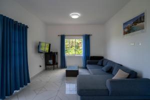 a living room with a blue couch and a tv at Creole Cottage Apartment in Anse Royale