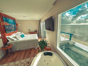 a bathroom with a tub and a bed and a window at Sollaris Ecopousada in Japaratinga