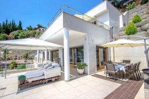 een huis met een patio met een bed en twee parasols bij Catalunya Casas Modern Magnificence , only a few km to the beach! in Sant Cebrià de Vallalta