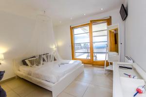 een witte slaapkamer met een groot bed en een raam bij Catalunya Casas Modern Magnificence , only a few km to the beach! in Sant Cebrià de Vallalta