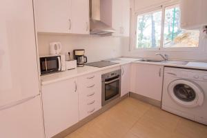 a kitchen with white cabinets and a washer and dryer at Catalunya Casas Fun and Frolic in Lloret del Mar 3500 meters to beach! in Lloret de Mar
