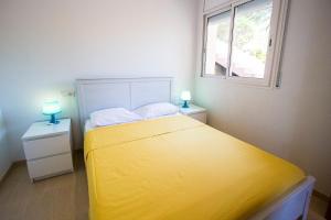 1 dormitorio con 1 cama amarilla y 2 mesitas de noche con lámparas en Catalunya Casas Fun and Frolic in Lloret del Mar 3500 meters to beach!, en Lloret de Mar
