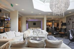 a living room with white furniture and a chandelier at Hotel Rosenstock - Erwachsenenhotel - Adults only 15 plus in Fischen