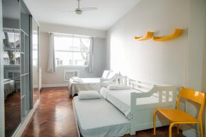 Habitación pequeña con 2 camas y silla en Apartamento confortável na quadra da praia, en Río de Janeiro