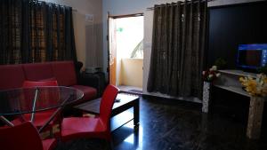 a living room with a glass table and red chairs at The Ventura Grand Hotel in Bangalore