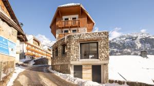 un edificio en una carretera cubierta de nieve frente a una montaña en Madame Vacances Hotel Les Cimes, en Vaujany